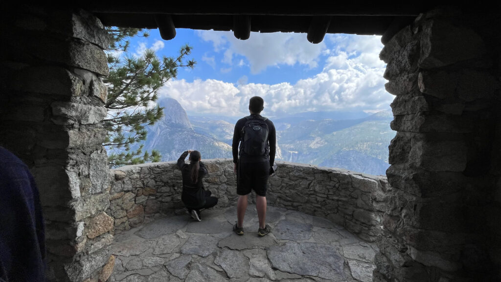 Me crouched down taking a photo in the small stone building at Glacier Point that you can enter to get some great views from in Yosemite National Park