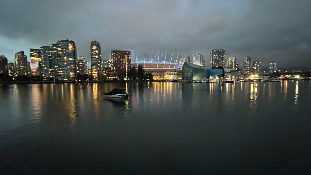 BC Place Stadium lit up in the center as seen from The Seawall in in Hinge Park in Vancouver, BC, Canada