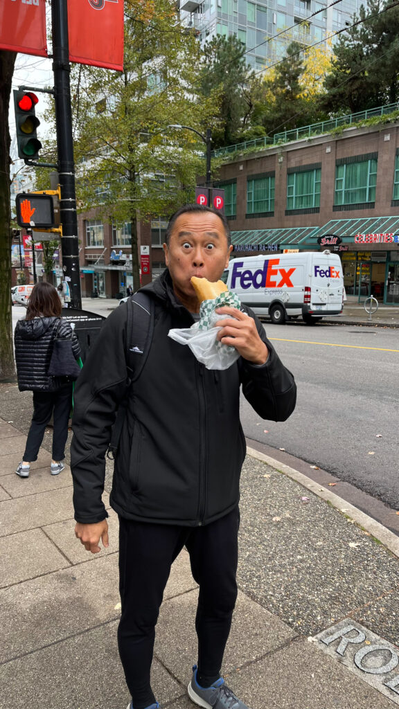 As we were walking down Robson Street my husband grabbed a bánh mì to go (As usual, he was making me laugh. He says his job is to make me laugh. He's very good at his job) (Vancouver, BC, Canada)