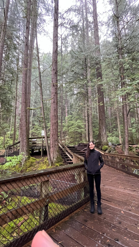 Me, keen to hike Twin Falls trail to the wooden bridge over the falls in Lynn Canyon Park (and my husband's thumb keen to get in the photo) (North Vancouver, BC, Canada)