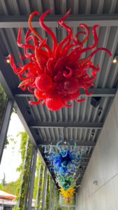 A series of glass artwork in various colors hanging from the ceiling of an outdoor walkway at Chihuly Garden and Glass. (Seattle, WA)