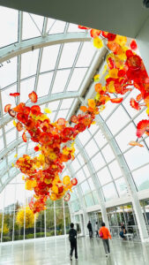 Large, hanging glass artwork in shades of red, orange and yellow in the glasshouse at Chihuly Garden and Glass. (Seattle, WA)