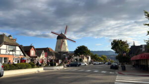 A windmill and other Danish style buildings in Solvang, CA with rolling hills in the background