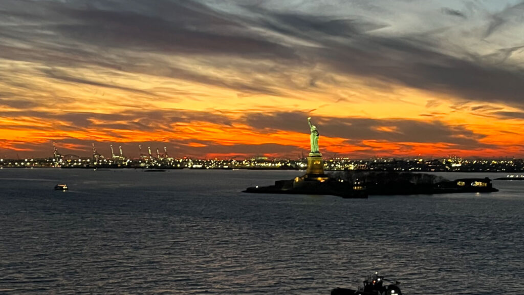 Sailing out of Manhattan, New York City, NY on the Carnival Venezia during sunset, zooming in on the Statue of Liberty in the distance