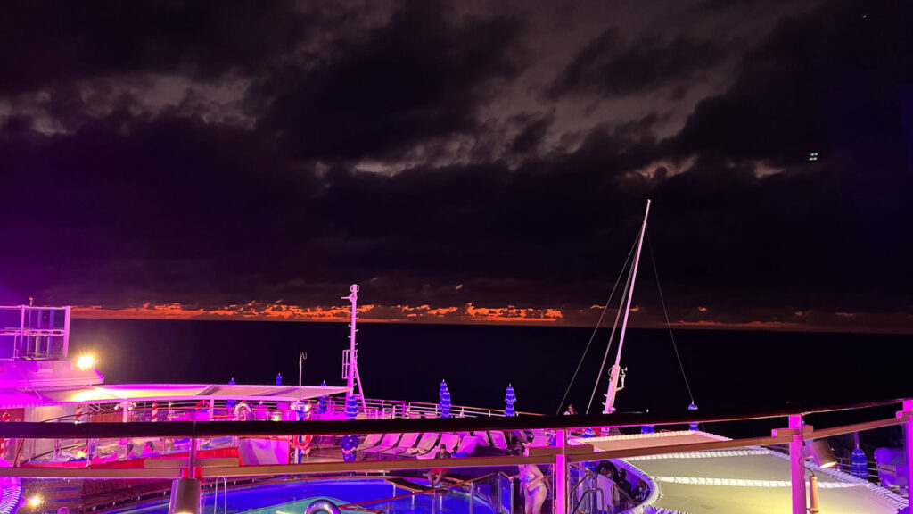 View of the aft of the Carnival Venezia and the orange-red horizon above the dark ocean