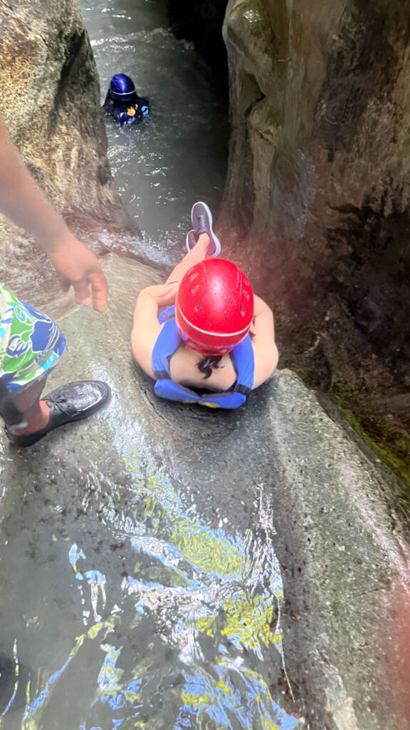 Me sliding down a slide at Damajagua 27 Falls in the Dominican Republic (Notice that I didn't pull my elbows in enough, which led to one of my elbows getting scraped and bruised a little, but it was no big deal) The guide gives you a push to get you going.