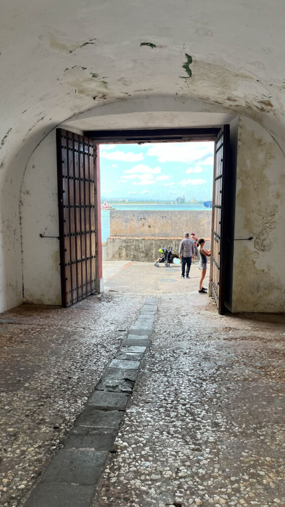 Looking through the San Juan Gate (Puerta de San Juan) (which is under the city wall) to the walkway we had just walked from that's between San Juan Bay and the city wall in San Juan, Puerto Rico (That's me on the right taking the photo that's just above this photo)