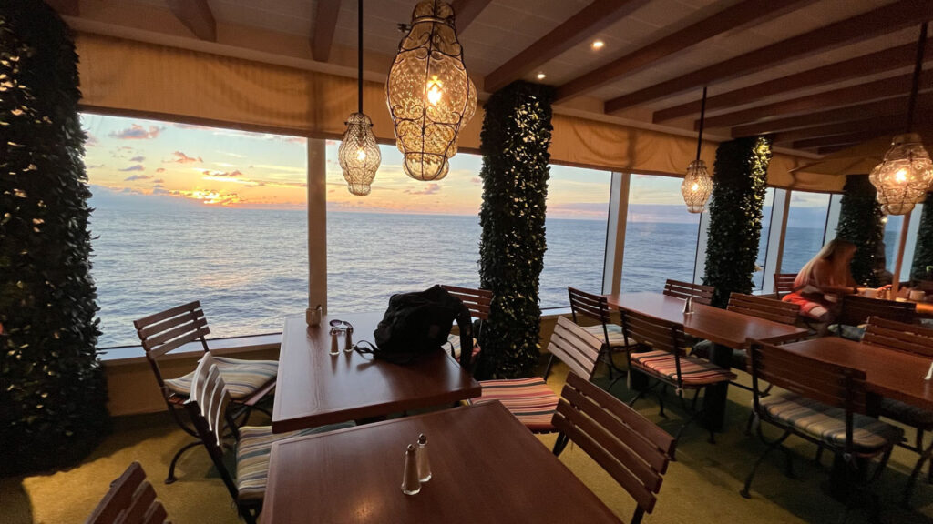 Carnival Venezia Lido Marketplace (photo was taken on a sea day) Beautiful sunset can be seen through the windows next to the dining tables and chairs.